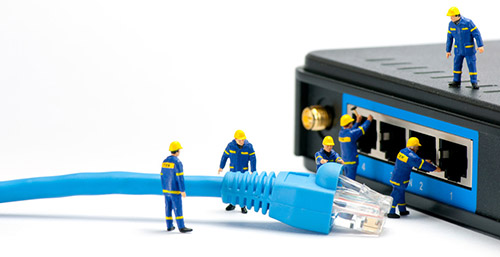 Técnicos en miniatura enchufando un cable de red en un router